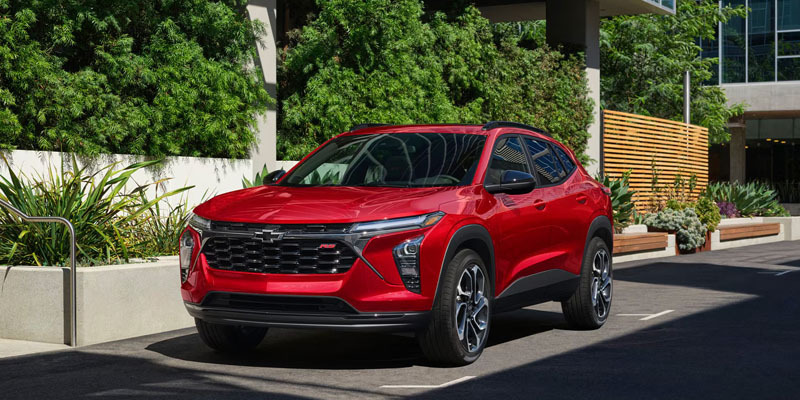 Front three-quarter view of a red Chevrolet Trax RS parked outdoors in an urban setting.